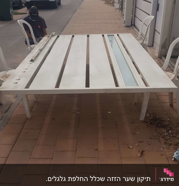 שער חשמלי לבן מונח על מדרכה עם כיסאות פלסטיק